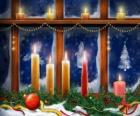 Χριστουγεννιάτικα κεριά αναμμένα μπροστά σε ένα παράθυρο